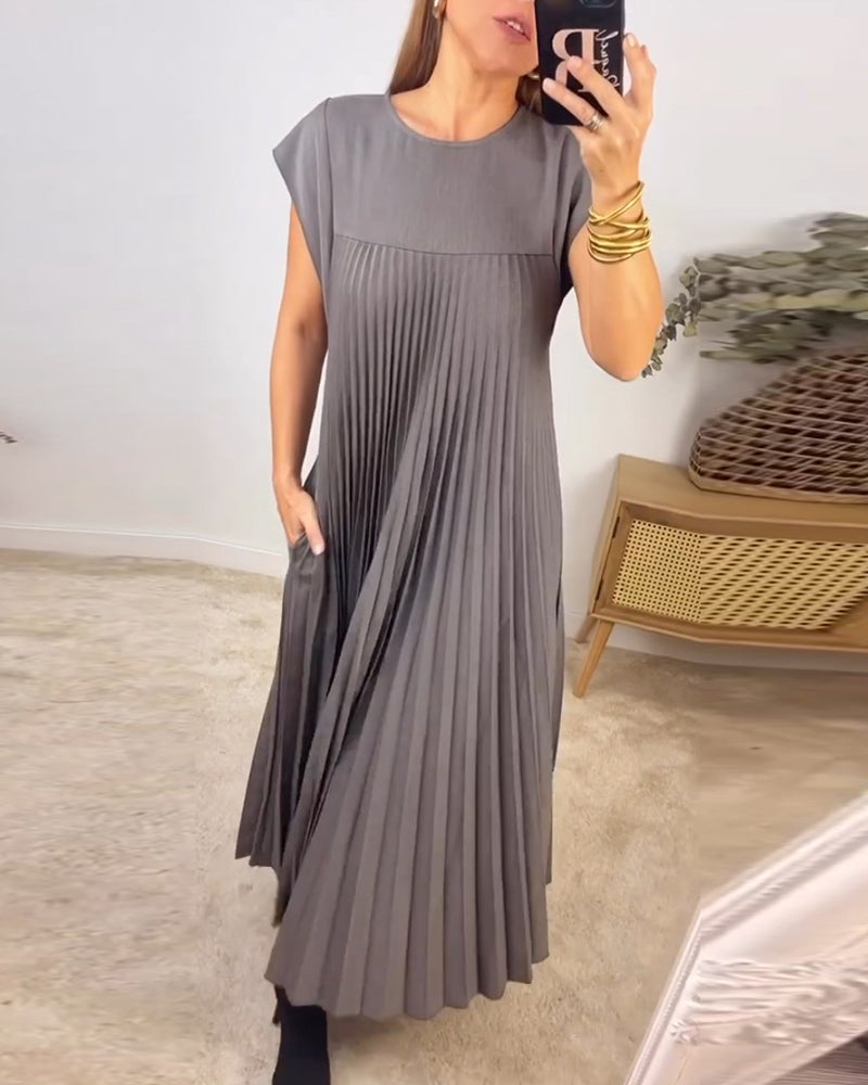 Woman wearing a chic pleated maxi dress, showing its flowing silhouette, elegant pleats & versatile design.