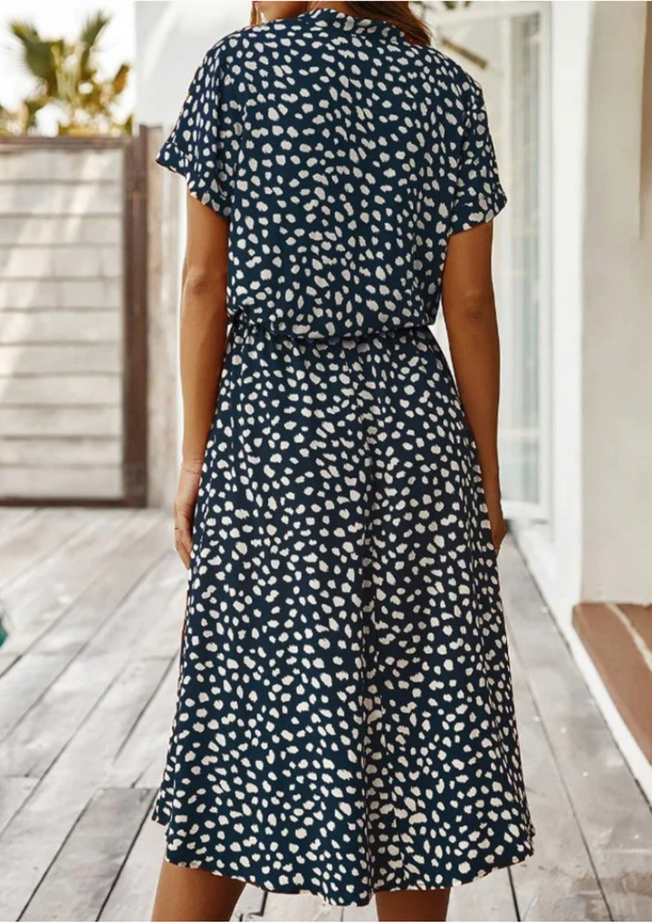 Woman posing confidently in versatile spotted button-down midi dress, suitable for day or evening.