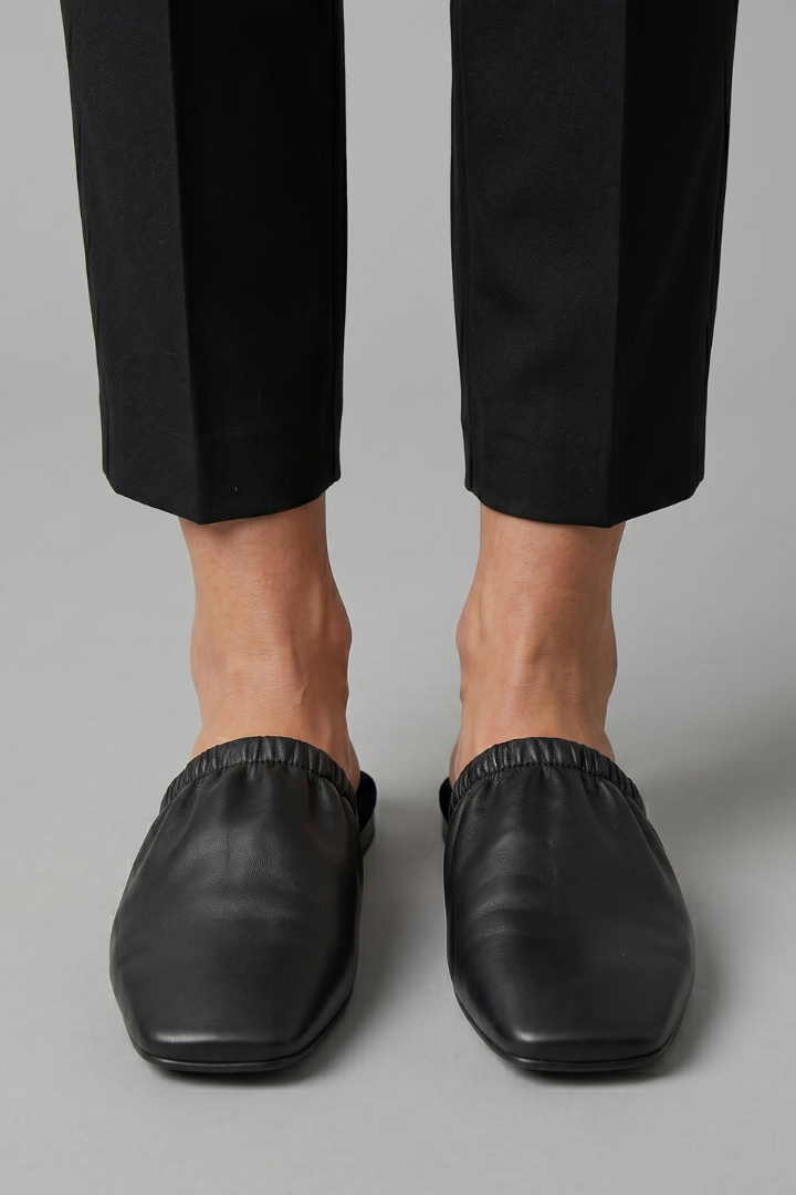 Elegant black women's cap toe slip-on mules. Flat, comfortable casual shoes for women's everyday footwear.