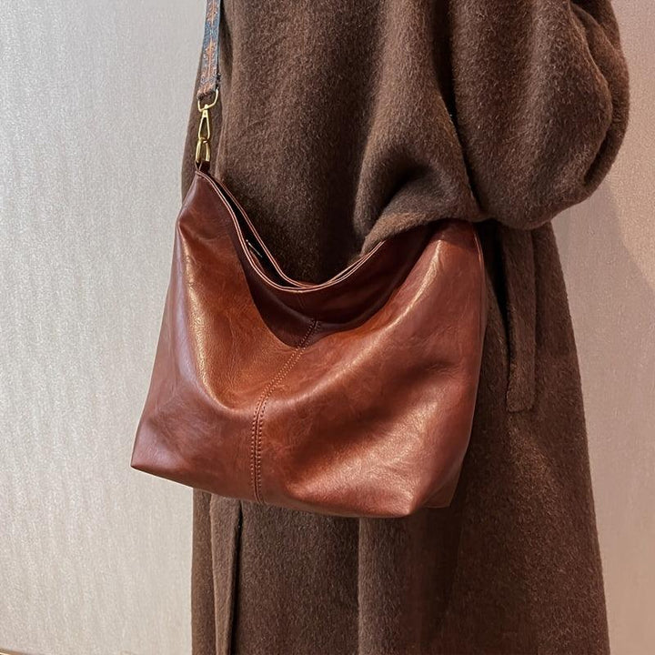 Faux leather bohemian shoulder bag for women, hobo style, featuring a colorful patterned strap. Chic accessory.