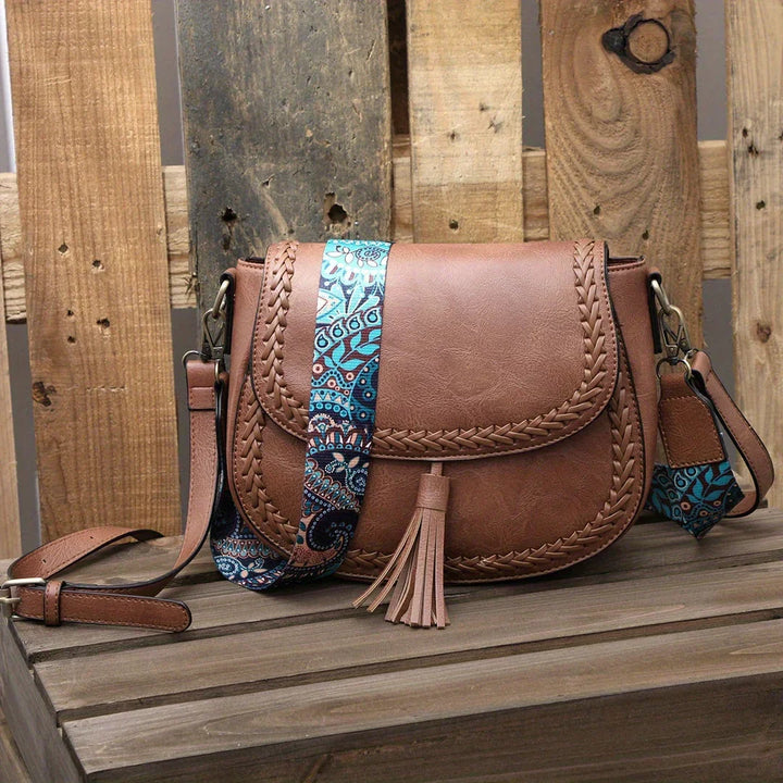 Chic black saddle bag for women, featuring elegant tassel. Versatile crossbody shoulder handbag and fashion accessory.