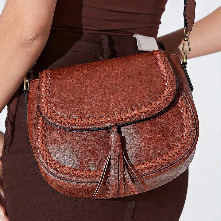 Brown elegant saddle bag with decorative tassel detail. Ideal women's chic crossbody shoulder bag for any occasion.