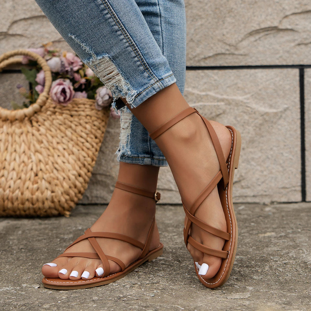 Flat open-toe women's sandals with an elegant buckle ankle strap, offering comfort for summer outings.