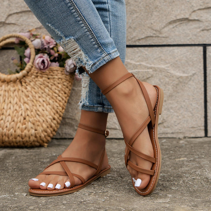 Flat open-toe women's sandals with an elegant buckle ankle strap, offering comfort for summer outings.