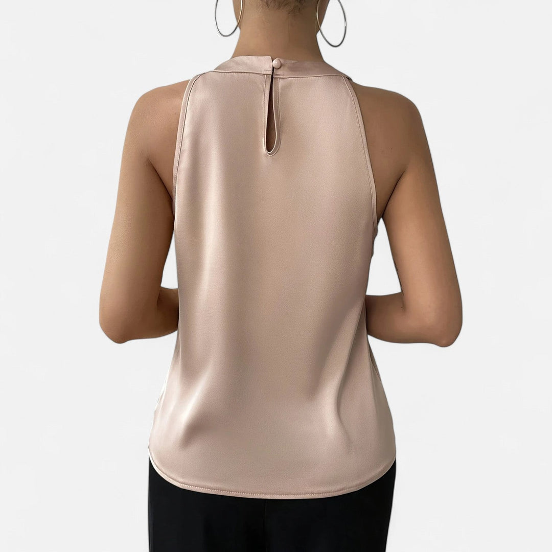 Close-up of the elegant pleated and draped front detail on a women's beige satin tank top.