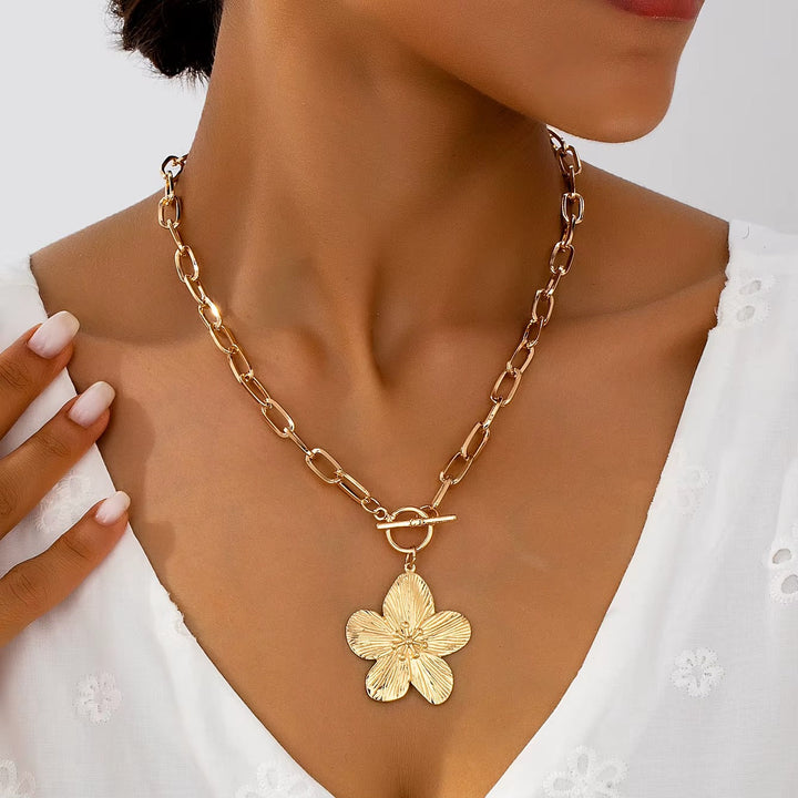Elegant gold-tone wisteria flower pendant necklace. Textured floral charm and stylish t-bar closure. Women's vintage jewelry.