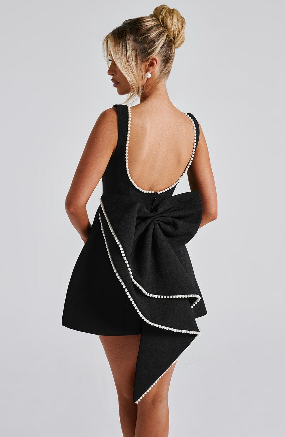Model wearing a black structured mini dress, showcasing its tailored fit and elegant design.
