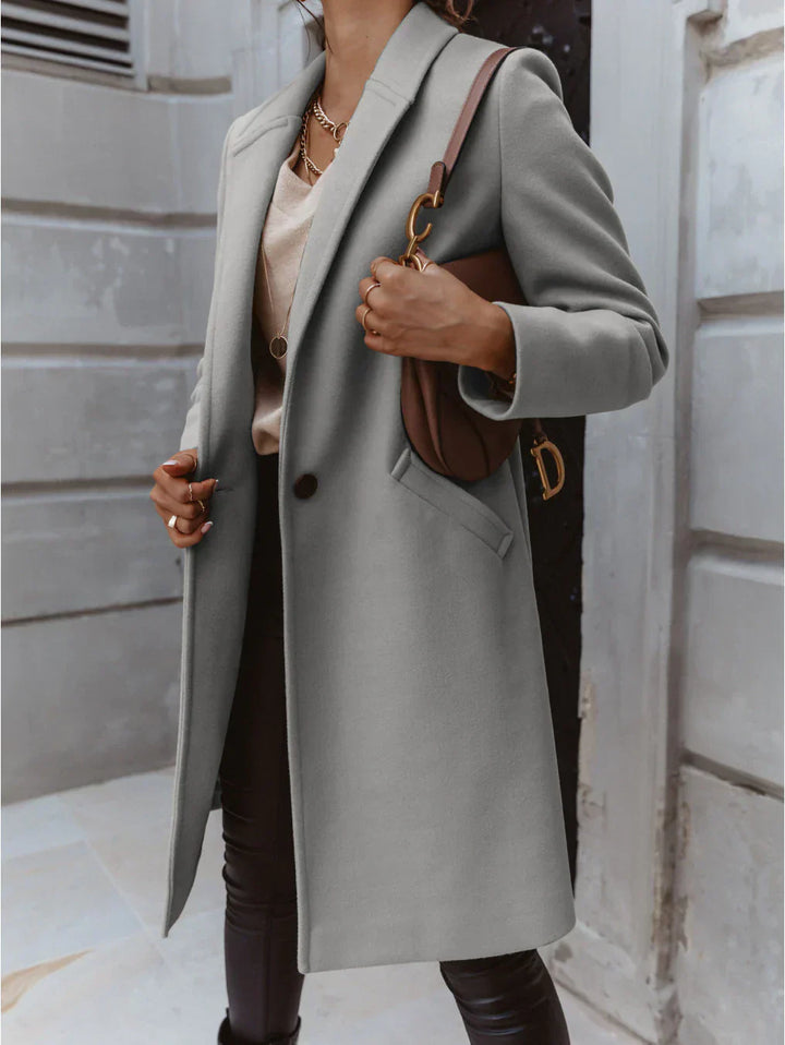 Front view of a women's double-breasted long trench coat with button details, essential outerwear.