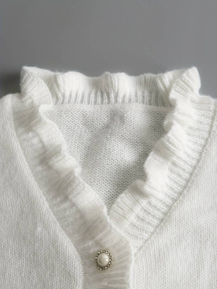 Stylish women's top: a white ruffle blouse with prominent decorative buttons and long sleeves.