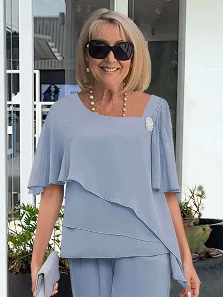 Stylish women's formal two-piece set with a sophisticated cape top and sleek trousers for evening wear.