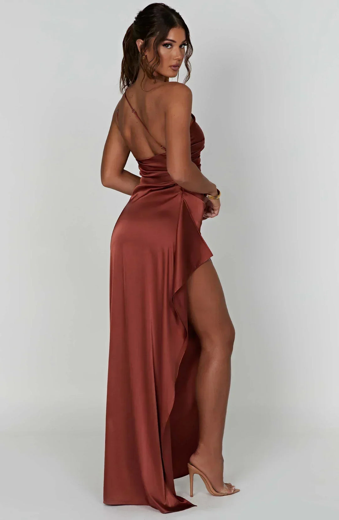 Model posing in a flowing white one-shoulder maxi dress, a perfect elegant party dress for women.