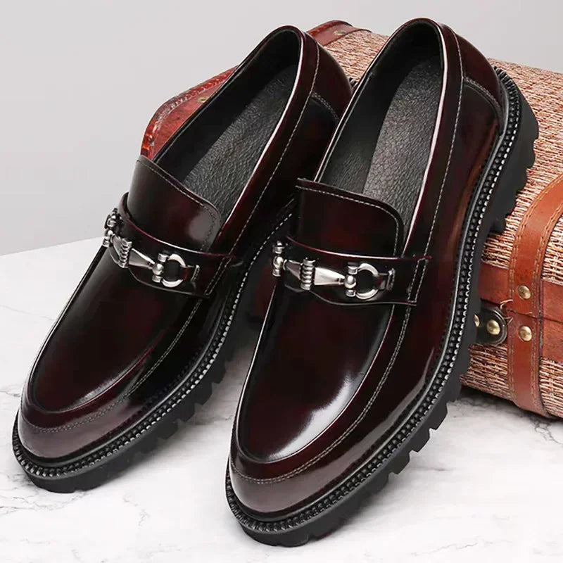 Side view of men's burgundy polished loafers. Formal dress shoes with a subtle metal bit detail.
