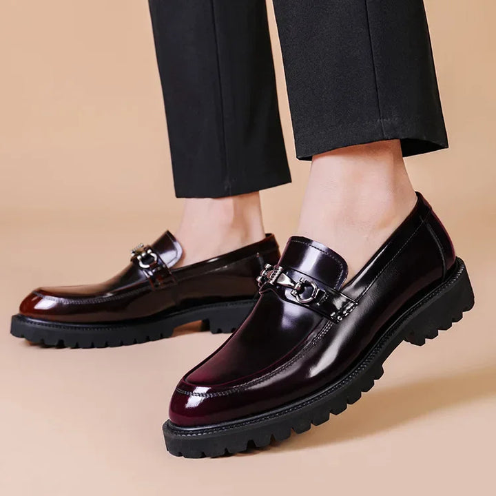 Close-up of polished black leather loafers, highlighting the elegant silver metal bit detail. Formal men's shoes.