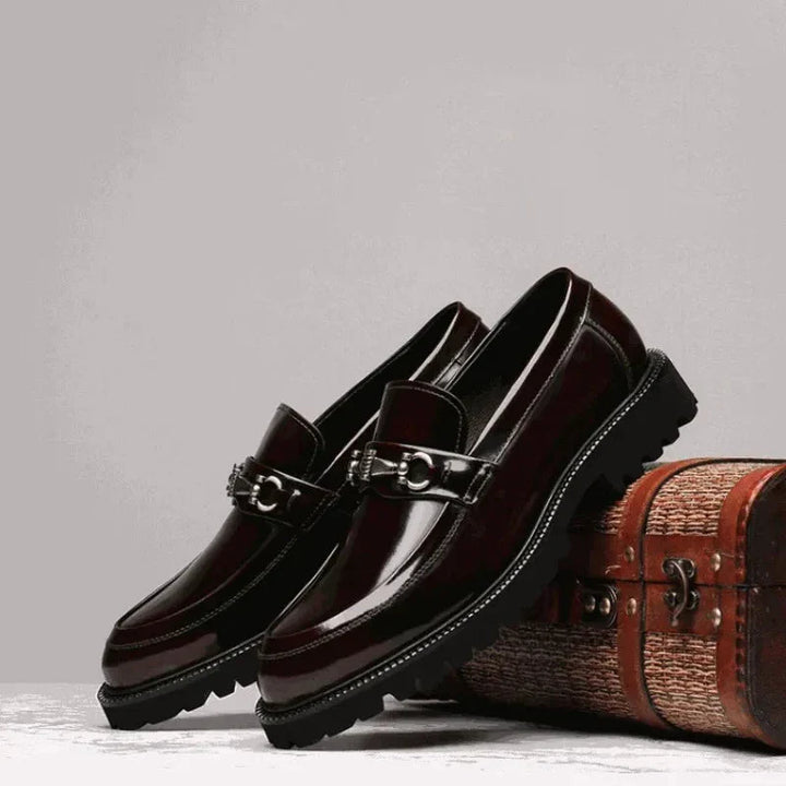 Men's polished black loafers with metal bit, worn with formal attire. Comfortable classic dress shoes.