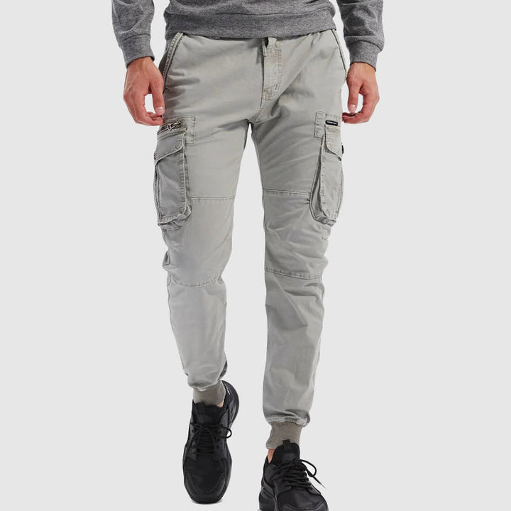 Men's slim fit cargo jogger pants in dark grey, featuring utility pockets, tapered leg, and comfortable drawstring waist.