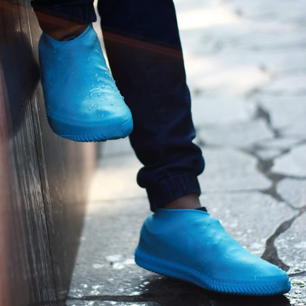 "Waterproof silicone shoe covers, anti-slip, foldable, unisex, shown covering shoes, durable and portable for any weather."