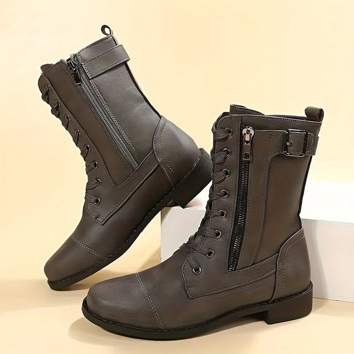 Close-up of a side zipper on women's combat boots, showcasing the durable metal hardware and boot texture.