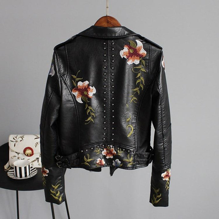 Close-up of floral embroidered faux leather biker jacket for women, featuring intricate stitching and a classic zip closure.