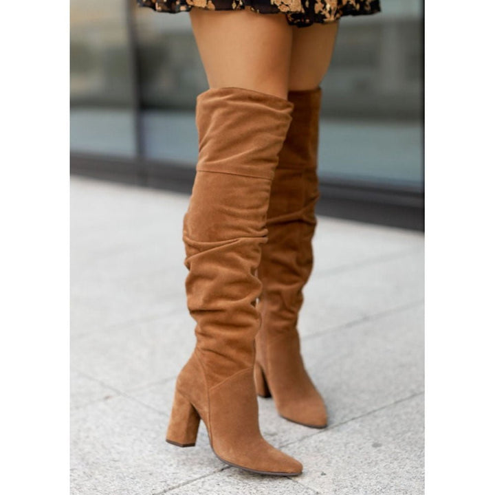 Close-up of women's black over-the-knee high heel boots with a pointed toe, showcasing elegant footwear.