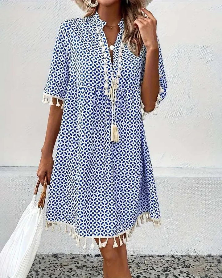 Lightweight blue geometric print mini dress with boho style and tassel accents, a must-have vacation outfit.