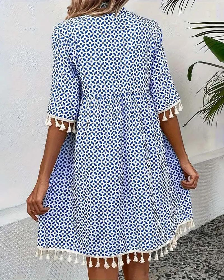 Trendy women's summer dress: blue boho mini tunic with a vibrant geometric pattern and chic tassel trim.