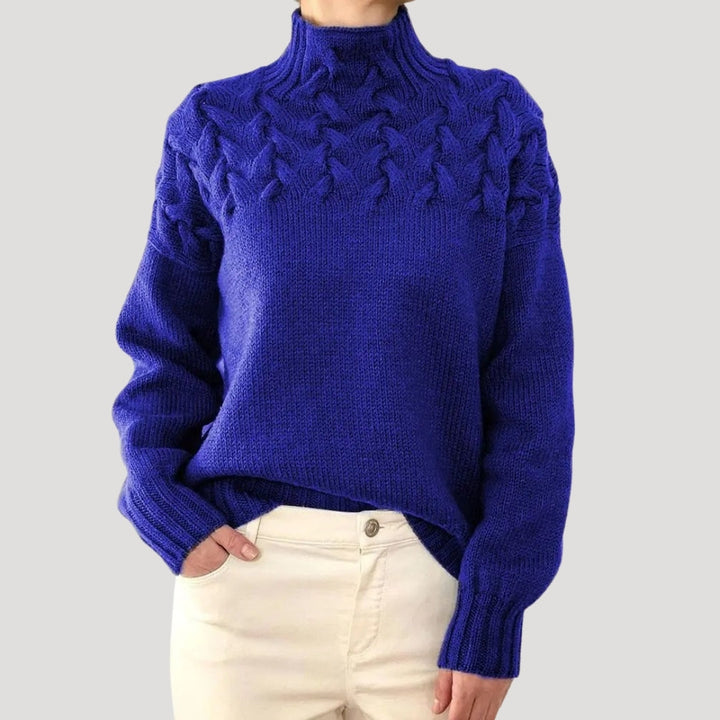 Close-up of a women's ivory cable knit high-neck sweater, showcasing intricate knit pattern and warmth.