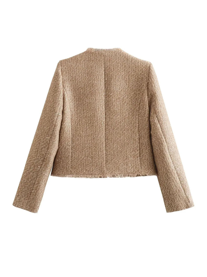 Close-up of a women's cropped tweed blazer, highlighting the intricate texture and chic design