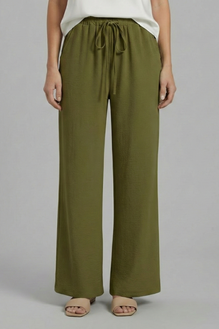 Hanged women's ankle-length trousers, elastic waist, side pockets, & tapered leg, ready for wear.