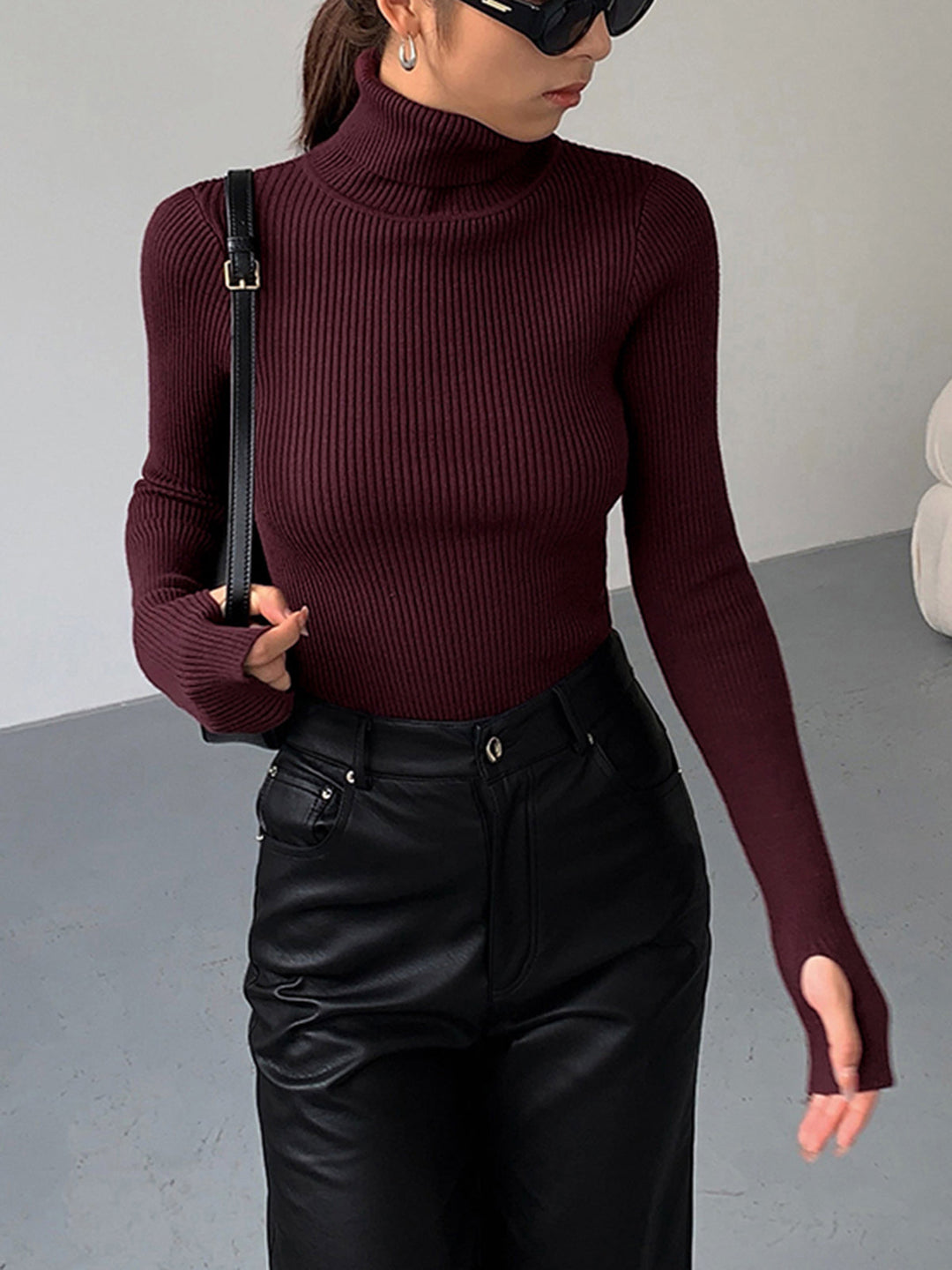 Model wearing a stylish gray ribbed knit turtleneck top, showcasing its elegant fit and long sleeves.