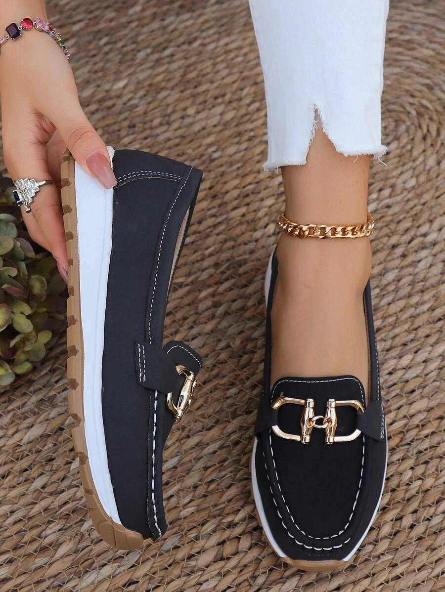 Close-up of elegant gold horsebit detail on classic women's loafers, showcasing premium style.