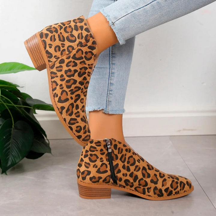 Close-up of a women's leopard print ankle boot, showing the detailed animal print and zipper.
