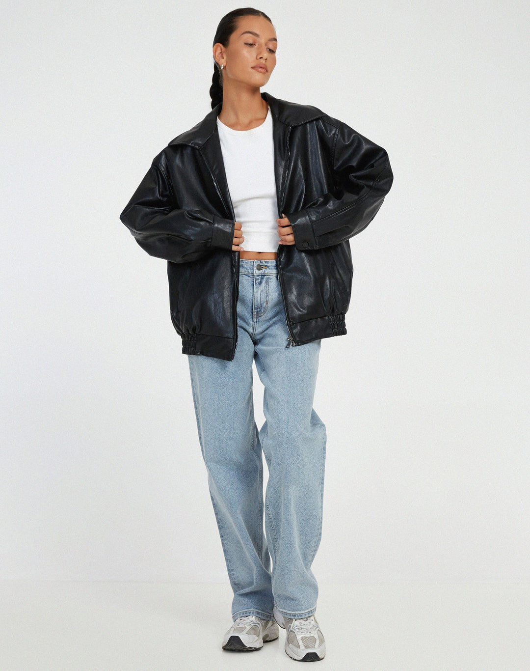 Model wearing a black oversized faux leather bomber jacket, styled casually for an everyday look.