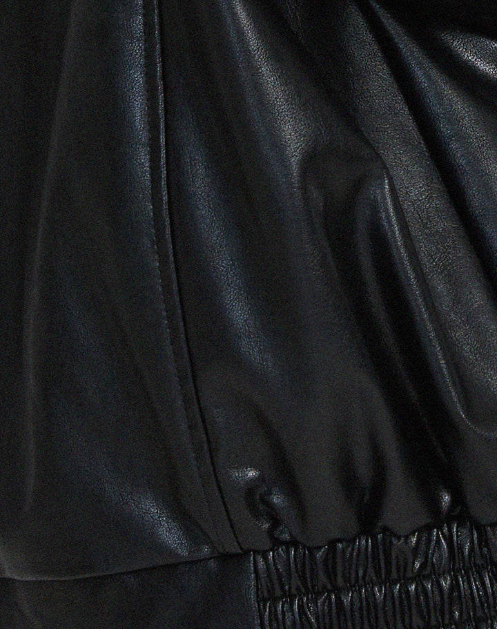 Side profile of a woman wearing an oversized brown faux leather bomber jacket, ideal for layering.