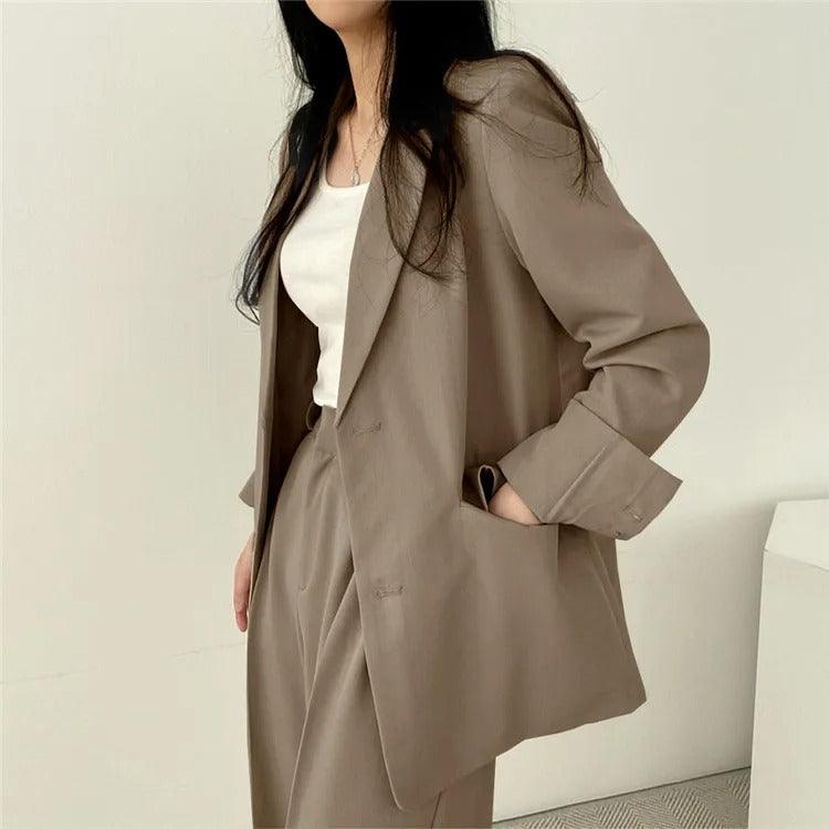 Empowering women's suit with a long tailored blazer and matching trousers, perfect for boardrooms.