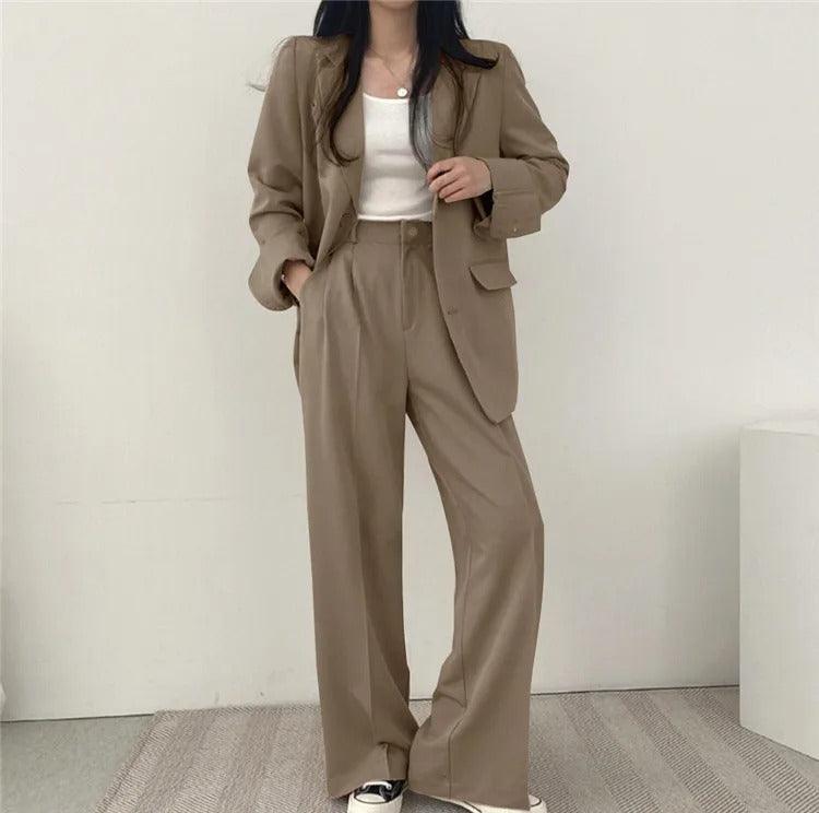 Minimalist women's tailored suit set, featuring a long blazer and clean-cut trousers for a sharp look.