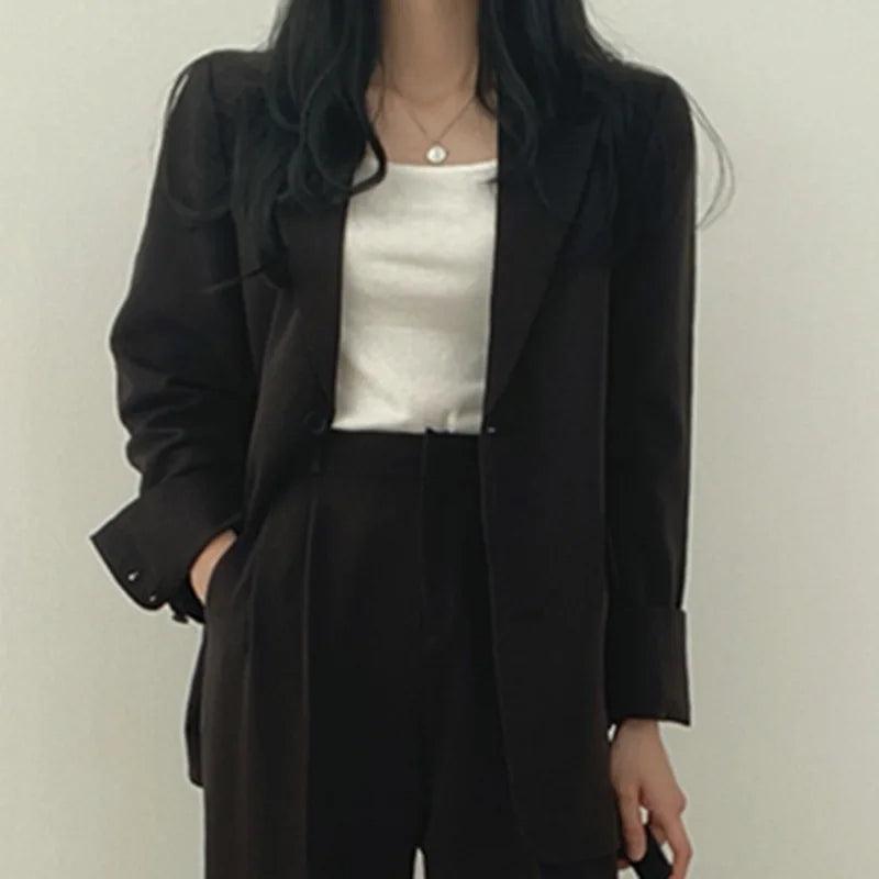 Refined women's tailored suit, showcasing a long blazer and elegant trousers, a staple for business.