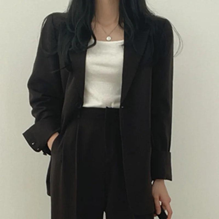 Refined women's tailored suit, showcasing a long blazer and elegant trousers, a staple for business.