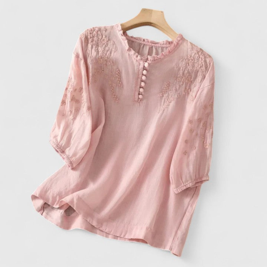 Feminine white embroidered blouse with a stylish ruffle collar, fun pom-pom details, and three-quarter sleeves for casual wear.