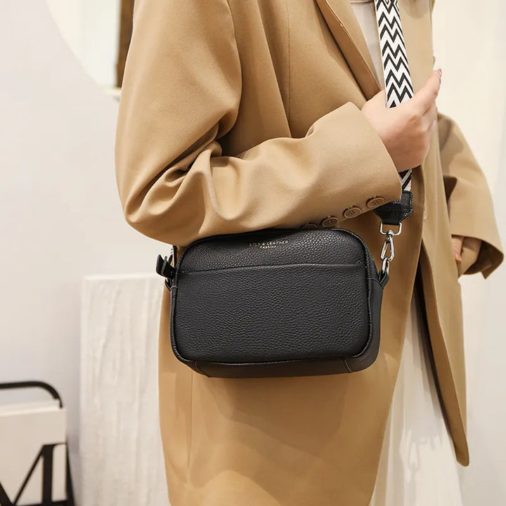 "Women's boxy camera bag with detachable chevron strap, pebbled texture, rectangular shape, and secure zip closure."