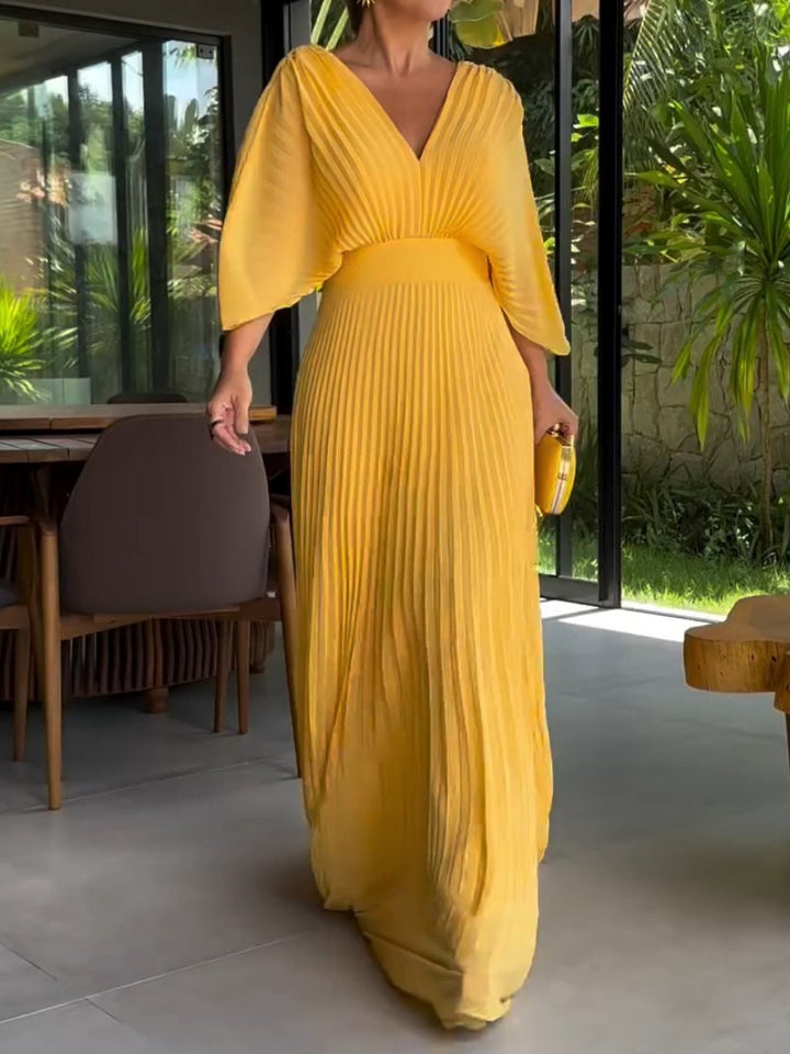 Women's pleated maxi dress with V-neck, batwing sleeves, defined waistband, elegant full-length, seen in front view.