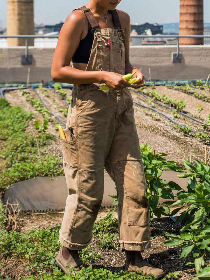 Women's utility bib overalls, adjustable straps, multi-patch pockets, wide-leg fit, durable, stylish canvas workwear.